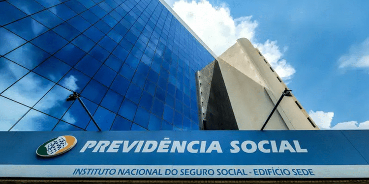 Foto da fachada do prédio sede da Previdência Social com logo e céu azul refletido no vidro.
