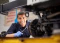Técnico em mecânica automotiva realizando manutenção com ferramenta.