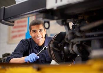 Técnico em mecânica automotiva realizando manutenção com ferramenta.
