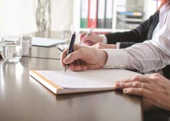 Profissional escriturário registrando informações em reunião administrativa