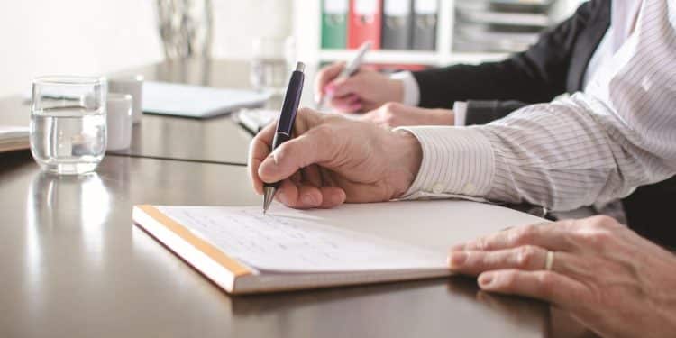 Profissional escriturário registrando informações em reunião administrativa