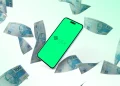 Celular exibindo logo do Pix com cédulas de 100 reais brasileiras ao redor em fundo branco