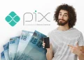 Homem sorrindo com celular na mão e notas de 100 reais ao fundo, logo do Pix Banco Central