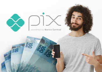 Homem sorrindo com celular na mão e notas de 100 reais ao fundo, logo do Pix Banco Central