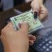 Mãos segurando a Carteira de Identidade Nacional brasileira com foto e dados pessoais durante processo de emissão no mutirão gratuito