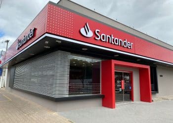 Fachada externa de uma agência do Banco Santander, com a logomarca vermelha em destaque. A imagem ilustra a abertura das inscrições para o Programa de Estágio com bolsa-auxílio.