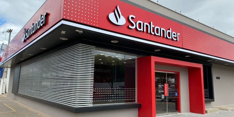 Fachada externa de uma agência do Banco Santander, com a logomarca vermelha em destaque. A imagem ilustra a abertura das inscrições para o Programa de Estágio com bolsa-auxílio.