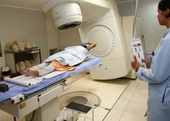 Mulher recebendo radioterapia em hospital com profissional de saúde operando aparelho