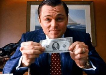 Leonardo DiCaprio vestido com terno segurando uma nota de dólar, cena icônica do filme O Lobo de Wall Street