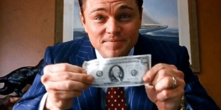 Leonardo DiCaprio vestido com terno segurando uma nota de dólar, cena icônica do filme O Lobo de Wall Street