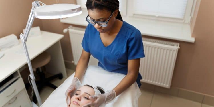 Esteticista aplica tratamento facial em cliente, ilustrando curso técnico de Estética.