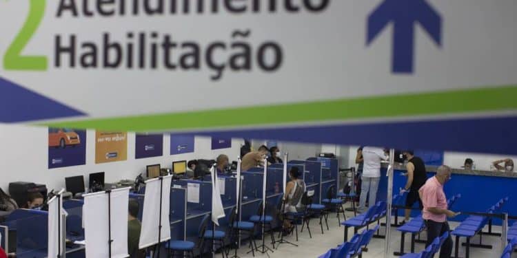 Atendimento no Departamento de Trânsito, com profissionais atendendo em balcões e pessoas aguardando em cadeiras.