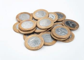 Pilha de moedas de R$ 1 do Plano Real, alertando sobre a moeda de 2016 com o erro do reverso invertido.