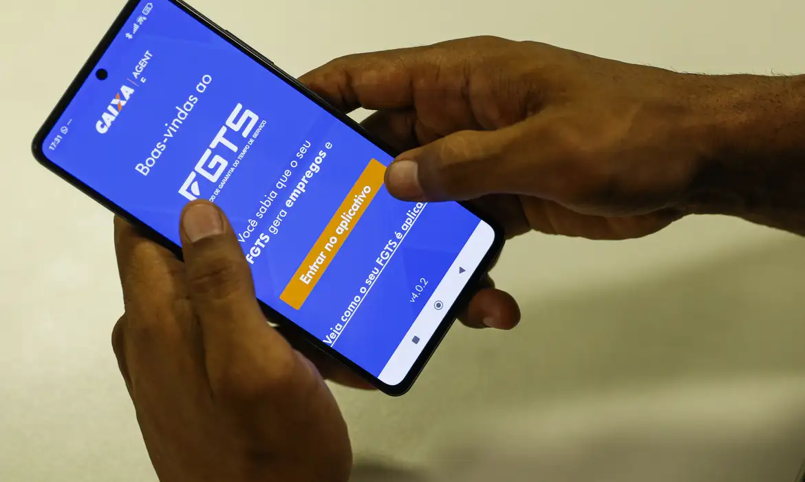 Pessoa segurando smartphone com o aplicativo FGTS da Caixa aberto na tela