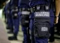 Guarda Municipal alinhada em formação vestindo uniforme azul com bolsa preta e identificação.