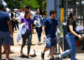 Grupo de jovens caminhando para fora do local de prova com documentos nas mãos em dia de vestibular