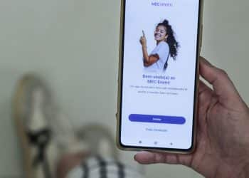Pessoa segura um celular exibindo a tela inicial do aplicativo MEC Enem.