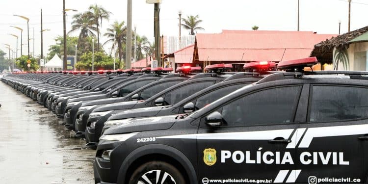 Várias viaturas pretas da Polícia Civil do Ceará alinhadas em fila sob chuva com sirenes vermelhas ligadas.