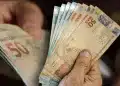 Mãos segurando notas de real representando o Saque Calamidade do FGTS liberado para trabalhadores afetados por desastres naturais