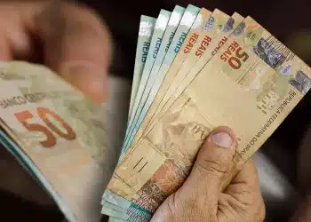Mãos segurando notas de real representando o Saque Calamidade do FGTS liberado para trabalhadores afetados por desastres naturais