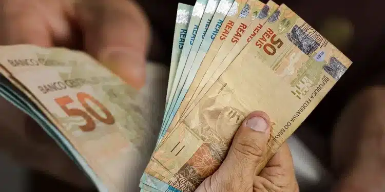 Mãos segurando notas de real representando o Saque Calamidade do FGTS liberado para trabalhadores afetados por desastres naturais