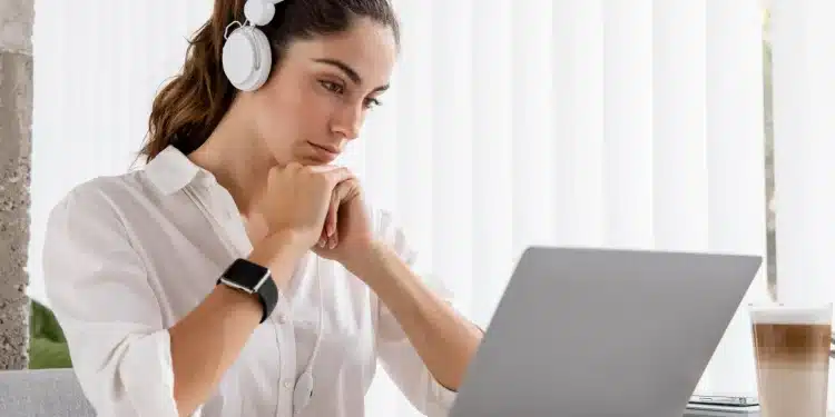 Mulher trabalhando em um laptop com fones de ouvido, representando a adaptação ao mundo digital por meio de cursos de formação.