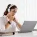 Mulher trabalhando em um laptop com fones de ouvido, representando a adaptação ao mundo digital por meio de cursos de formação.