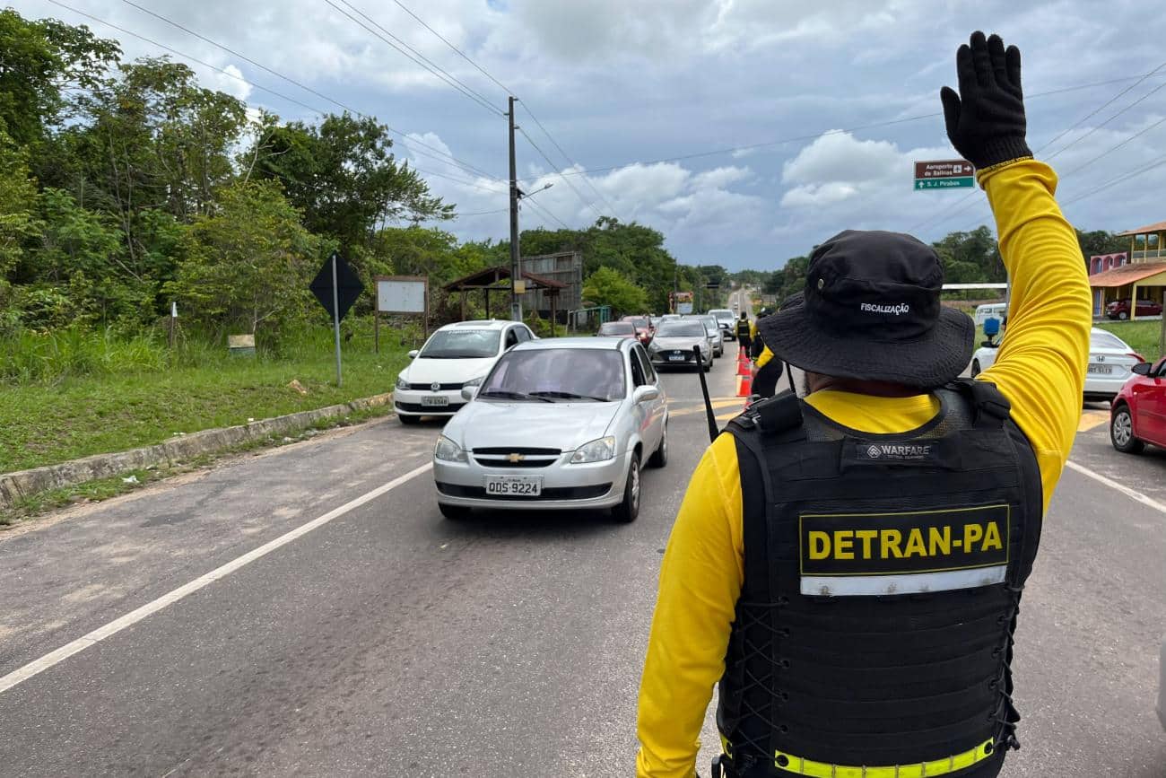 Agente de trânsito do DETRAN-PA controlando o tráfego em estrada com veículos em fila.