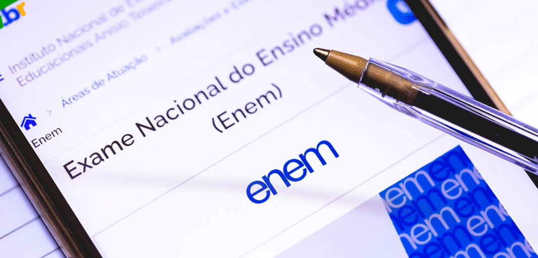 Tela de celular exibindo o site oficial do Enem com uma caneta apontada para o nome do exame.