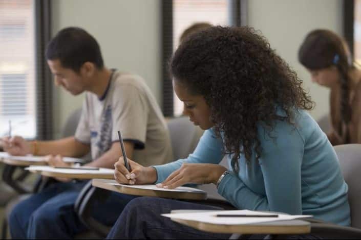Alunos diversos fazendo anotações em sala de aula, representando a formação profissional e técnica oferecida pelo SENAI-SP.