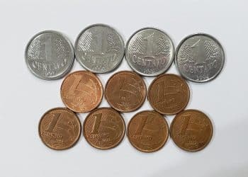 Coleção de moedas de 1 centavo de diversos anos, incluindo modelos antigos prateados e cobreados, sobre um fundo branco, ilustrando as raridades numismáticas.