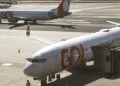 Dois aviões da Gol estacionados no aeroporto com um ligado à ponte de embarque