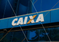 Fachada de prédio azul com logo branco e amarelo da Caixa Econômica Federal.