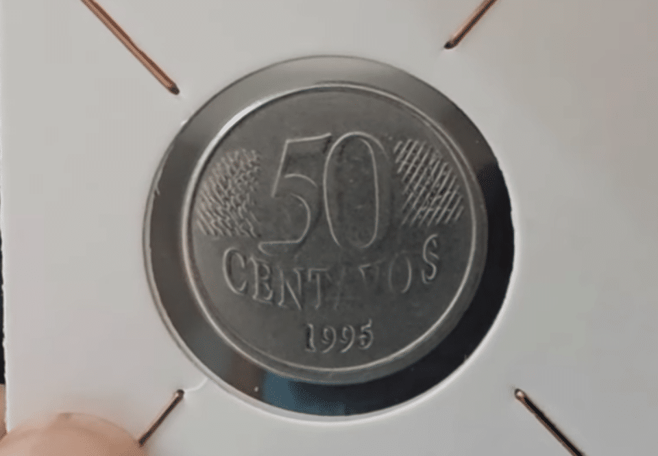 Moeda de 50 Centavos de 1995 em um suporte de colecionador, evidenciando o ano e o valor, sendo um exemplar raro e híbrido (mula) de alto valor na numismática.