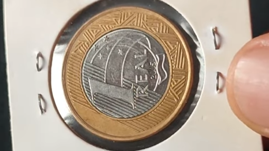 Moeda de 1 Real Rara - Anomalia de Cunhagem Moeda de 1 Real acondicionada, mostrando o reverso e o edifício inclinado à esquerda, característica de uma moeda rara e valiosa.