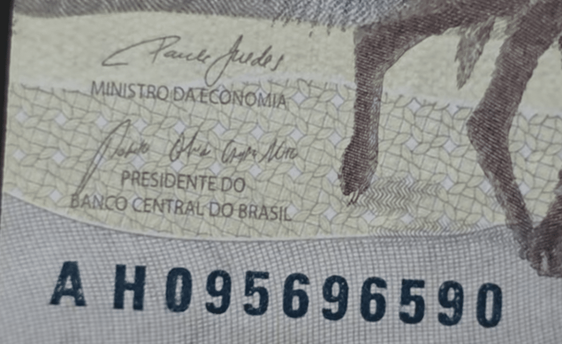 Cédula 200 Reais Rara Série AH Numeração Valiosa Close-up da cédula de R$ 200, mostrando a assinatura do Ministro da Economia e a série "AH", indicando uma tiragem limitada de 2.200.000 exemplares, muito procurada por colecionadores de notas raras.