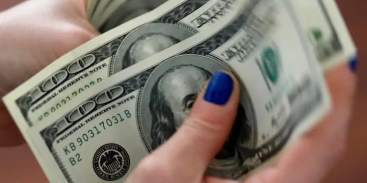 Mãos femininas com unhas azuis segurando várias notas de cem dólares americanos