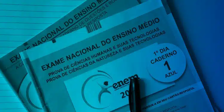Cadernos do ENEM 2025 com caneta preta sobre mesa azul