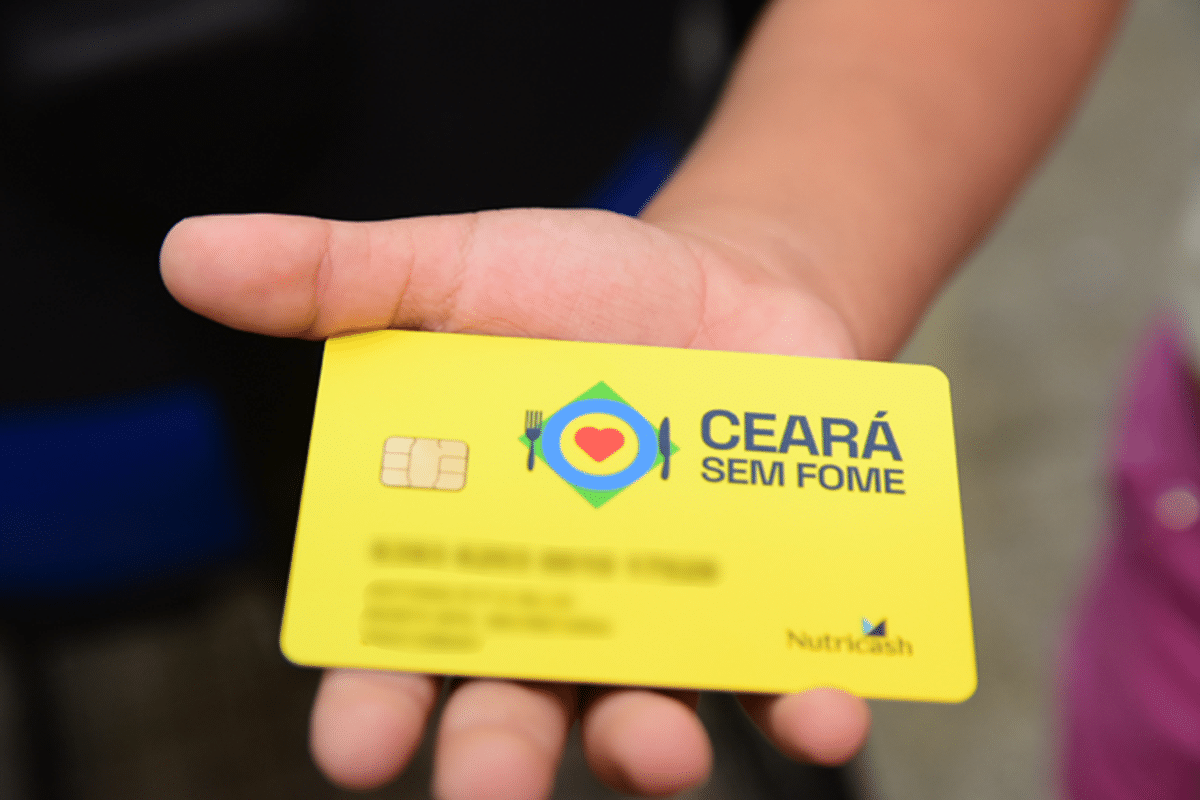 Cartão amarelo do programa Ceará Sem Fome sendo exibido em mão de beneficiário
