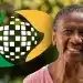 Idosa negra sorridente com camiseta rosa e logo de milho verde e amarelo em fundo desfocado de natureza