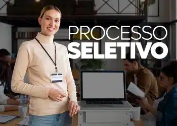 Mulher sorridente com crachá apresentando processo seletivo em escritório moderno e equipe ao fundo