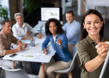 Grupo de profissionais em reunião com mulher escrevendo no quadro branco durante apresentação.