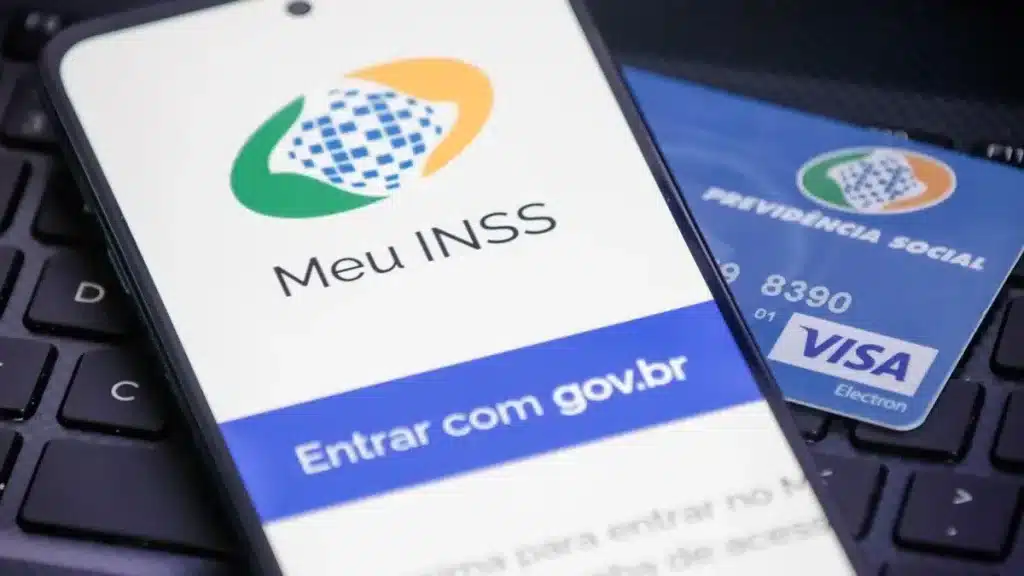 Smartphone exibindo o aplicativo "Meu INSS" com a opção "Entrar com gov.br", ao lado de um cartão do "Previdência Social" com logo Visa Electron, simbolizando a interação digital com o INSS e a necessidade de segurança.