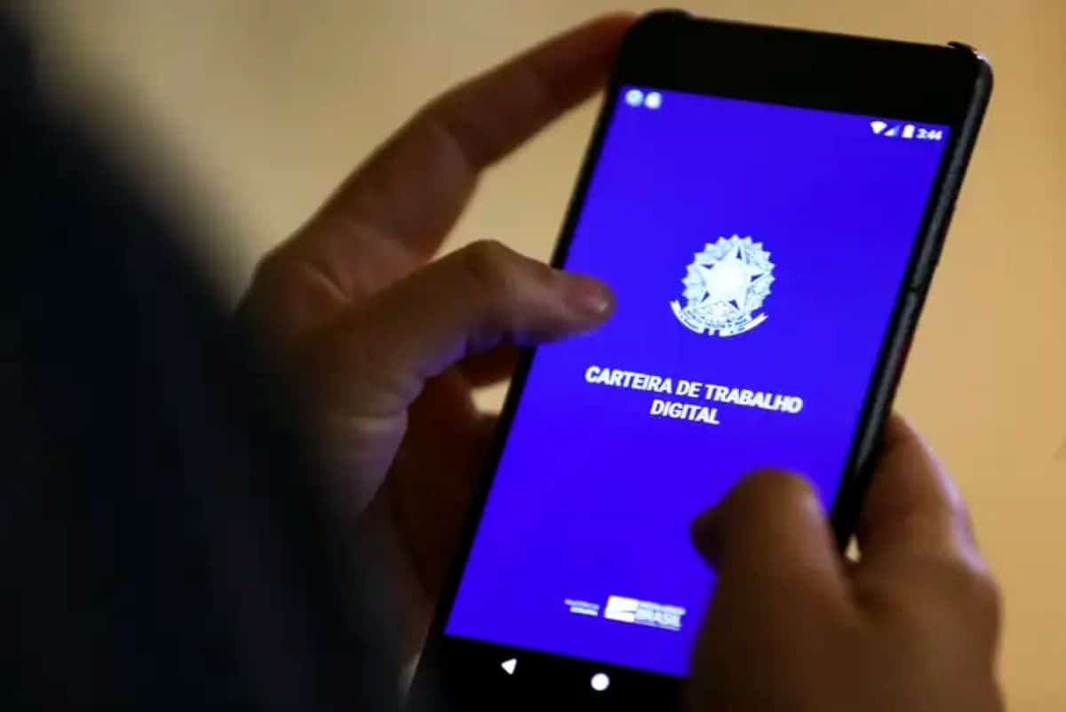 Pessoa consultando a Carteira de Trabalho Digital no celular, representando como verificar se está na lista de beneficiados.