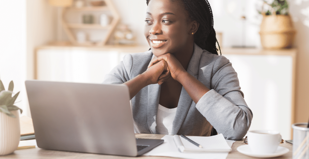 Mulher empreendedora e feliz, em um escritório doméstico, navegando em seu notebook em busca de vagas de emprego remoto.