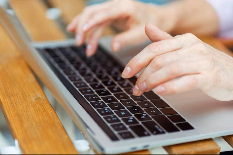 Mãos digitando em teclado de notebook, simbolizando a produtividade de profissionais que buscam carreiras solo e autonomia. Perfeito para ilustrar o trabalho de desenvolvedores, redatores ou tradutores.