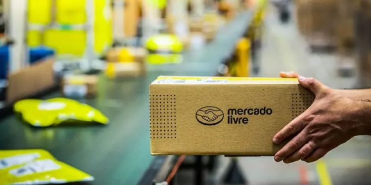 Pacote do Mercado Livre sendo manuseado em esteira de centro de distribuição, ilustrando o fluxo logístico rápido e eficiente para motoristas parceiros.