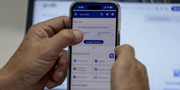 Mão segurando celular com app Meu INSS aberto mostrando consulta de benefício e serviços.