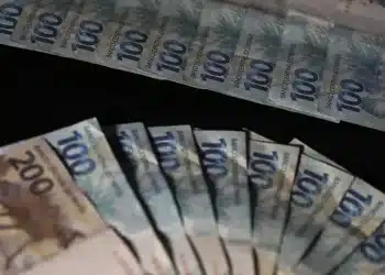 Sequência de notas de cem e duzentos reais enfileiradas representando pagamento extra governamental de até R$ 1.518
