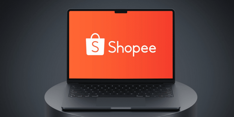 Laptop aberto com tela exibindo o logo branco Shopee sobre fundo laranja